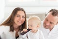 Parents sitting on the sofa. Their beautiful baby girl playing with cell phone. Royalty Free Stock Photo