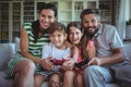 Parents sitting on sofa with their children and playing video games Royalty Free Stock Photo