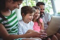 Parents sitting on sofa with their children and using laptop in living room Royalty Free Stock Photo