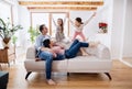 Parents with small daughters sitting on sofa indoors at home, relaxing.