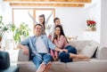 Parents with small daughters sitting on sofa indoors at home, relaxing.