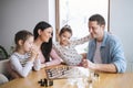 Parents with small girls indoors at home, playing board games. Royalty Free Stock Photo
