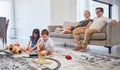 Parents on sofa, happy and watch children with toys on the living room floor and home. Mom relax with dad on couch in Royalty Free Stock Photo