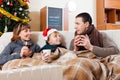Parents and son with cups of tea warming near warm calorifer Royalty Free Stock Photo