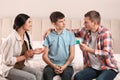 Parents talking with their teenage son about contraception in bedroom. Sex education concept