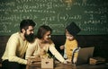 Parents teaches son, chalkboard on background. Modern education concept. Smart child in graduate cap likes to study