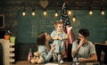 Parents teaching son american traditions playing. Kid with parents in classroom with usa flag, chalkboard on background Royalty Free Stock Photo