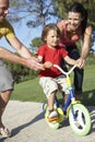 Parents Teaching Son To Ride Bike In Park Royalty Free Stock Photo