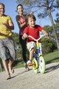 Parents Teaching Son To Ride Bike In Park Royalty Free Stock Photo