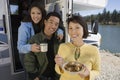 Parents and teenage daughter eating breakfast in RV at lake