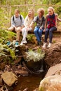 Parents and teens sitting on a bridge in a forest, vertical Royalty Free Stock Photo