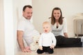 Parents and their beautiful baby girl sitting on the ground and playing. Royalty Free Stock Photo