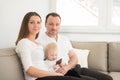 Parents and their beautiful baby girl sitting on the sofa and looking at the camera. Royalty Free Stock Photo