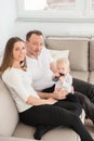 Parents and their beautiful baby girl sitting on the sofa and looking at the camera. Royalty Free Stock Photo