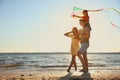 Happy parents and their child playing with kite on beach near sea. Spending time in nature Royalty Free Stock Photo