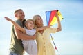 Happy parents with their child playing with kite on beach. Spending time in nature Royalty Free Stock Photo