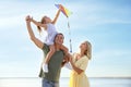 Happy parents with their child playing with kite on beach. Spending time in nature Royalty Free Stock Photo