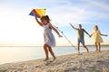 Happy parents with their child playing with kite on beach. Spending time in nature Royalty Free Stock Photo