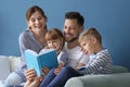 Parents and their children reading book together at home Royalty Free Stock Photo