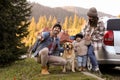 Parents, their daughter and dog near car in mountains. Family traveling with pet