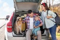 Parents, their daughter and dog sitting in car trunk outdoors. Family traveling with pet Royalty Free Stock Photo