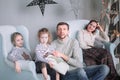 Parents with their little daughters sitting in the living room Christmas evening. Royalty Free Stock Photo