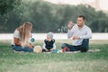 Parents and their little son blowing bubbles on a summer day walk. Royalty Free Stock Photo