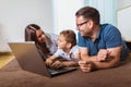 Parents and their son are doing shopping online using laptop and smiling at home Royalty Free Stock Photo