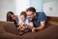 Parents and their son are doing shopping online using laptop and smiling at home Royalty Free Stock Photo