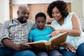 Parents and their son looking at photo album in living room Royalty Free Stock Photo