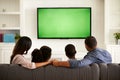 Parents and their two children watching TV together at home Royalty Free Stock Photo
