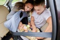 Parents tighten child car seat harness tightly before trip. Royalty Free Stock Photo