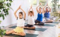 Parents together with children in yoga pose agni stambhasana