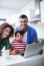 Parents using laptop with son in kitchen Royalty Free Stock Photo