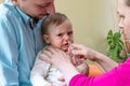 Parents using the nasal aspirator to clear the mucus from the nose of their infant. Royalty Free Stock Photo