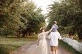 Parents are walking down the road in garden. Guy is caring their son on his shoulders Royalty Free Stock Photo