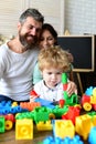 Parents watch their son with happy faces making brick constructions. Royalty Free Stock Photo