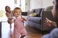 Parents Watching Baby Daughter Take First Steps At Home Royalty Free Stock Photo