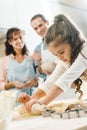 parents watching how serious little daughter rolling out dough Royalty Free Stock Photo