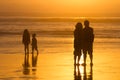 Parents watching kids play silhouettes, sunset on beach