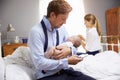 Parents With Young Baby Dressing For Work In Bedroom Royalty Free Stock Photo