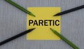 PARETIC - word on a yellow piece of paper on a gray background and pencils