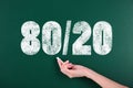 Pareto principle concept. Woman writing 80/20 on chalkboard