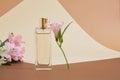 Parfum with flowers on beige brown background. A perfume bottle and white and pink lottle lily flowers