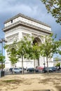 Paris, France, 09.10.2019: The Arc de Triomphe in the green of the trees against the blue sky on a sunny day. Side view.