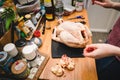 Woman removing fat from fresh Capon Chapon cockerel meat on kitchen wooden top