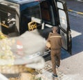 Aerial view of UPS driver in uniform next to his brown van loading unloading