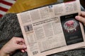 POV of senior hands holding latest Financial Times newspaper featuring article