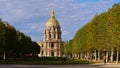 Front view of historic Les Invalides dome with golden colored cupola framed by a symmetric arrangement of trees.