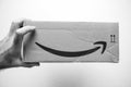 Hand holding cardboard box with Amazon Logotype Smile logo